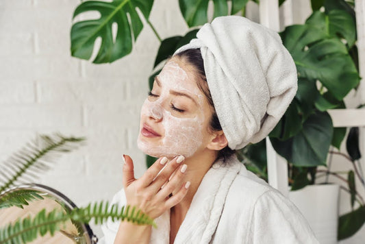 Woman in a bathrobe applying a homemade face scrub after a shower.