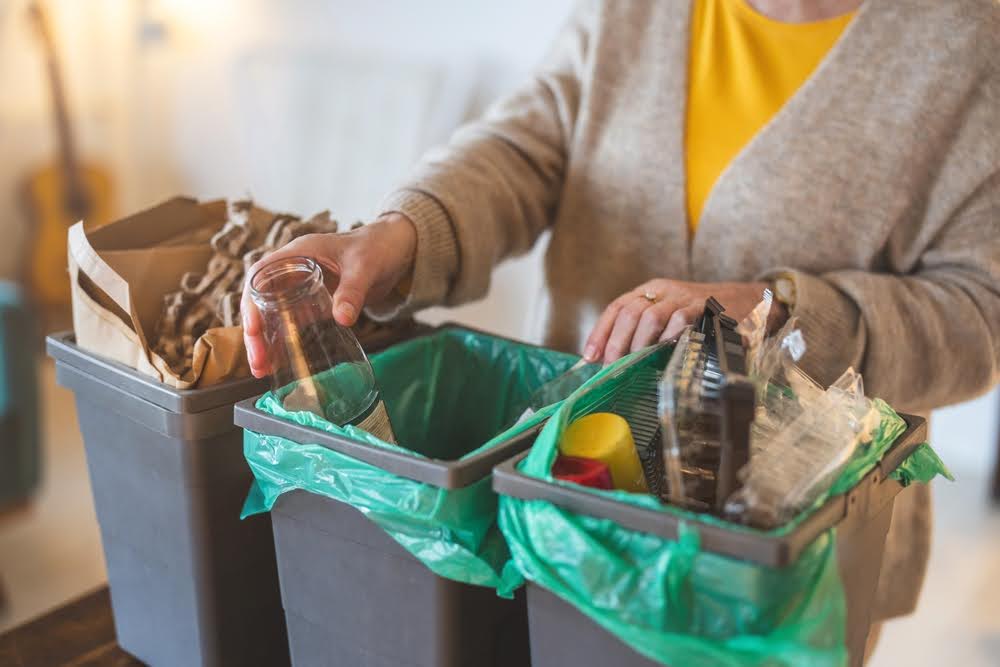 Zero-waste lifestyle: a woman sorting household waste into separate bins.